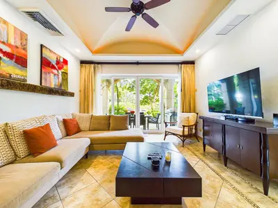 a living room with a couch and a tv at Matapalo 101- 3 Bedroom Poolside Luxury Condo At Tamarindo in Tamarindo