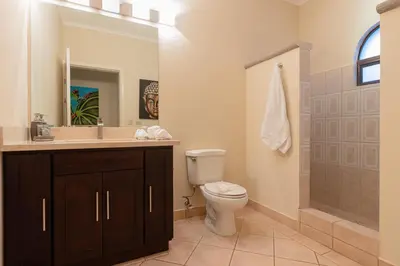 a bathroom with a toilet and a sink and a mirror at Sunrise 48- 3 Bedroom Ocean View Penthouse Condo in Tamarindo