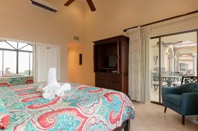 a bedroom with a bed and a chair and a balcony at Sunrise 48- 3 Bedroom Ocean View Penthouse Condo in Tamarindo
