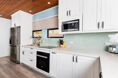 a kitchen with white cabinets and a stainless steel refrigerator at Flamingo Marina Cove 404- Oceanfront Condo in Playa Flamingo