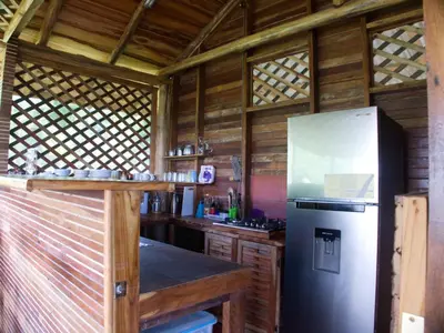 a kitchen with a stainless steel refrigerator and wooden walls at Finca Colibri, vue incroyable sur le Golfe de Nicoya, en Pleine Nature, ferry Playa Najanjo in Cabo Blanco