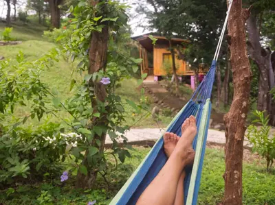 a person laying on a hammock in a garden at Finca Colibri, vue incroyable sur le Golfe de Nicoya, en Pleine Nature, ferry Playa Najanjo in Cabo Blanco