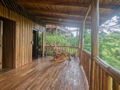 a porch of a house with rocking chairs on it at Finca Colibri, vue incroyable sur le Golfe de Nicoya, en Pleine Nature, ferry Playa Najanjo in Cabo Blanco