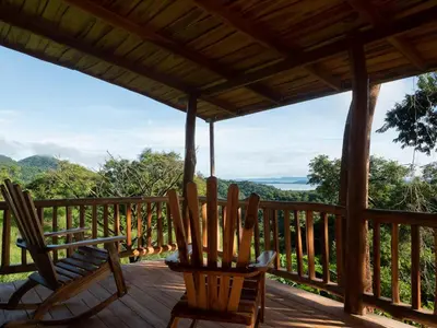 a porch with chairs and a view of the mountains at Finca Colibri, vue incroyable sur le Golfe de Nicoya, en Pleine Nature, ferry Playa Najanjo in Cabo Blanco