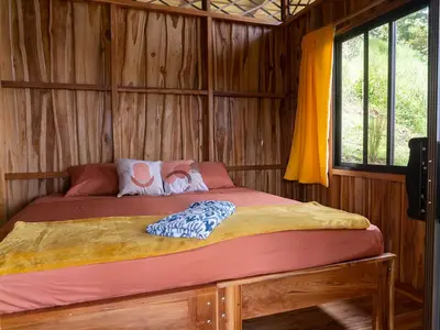 a bedroom with a bed in a wooden cabin at Finca Colibri, vue incroyable sur le Golfe de Nicoya, en Pleine Nature, ferry Playa Najanjo in Cabo Blanco