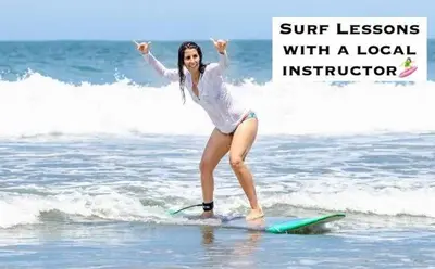 a woman standing on a surfboard in the ocean at Pipa's Surf House Marbella Guanacaste in Cuajiniquil