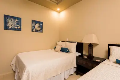a bedroom with two beds and a table with a lamp at Matapalo 605- 2 Bedroom Ocean View Condo At Tamarindo in Tamarindo