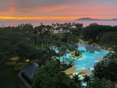 an aerial view of a resort swimming pool at sunset at Matapalo 605- 2 Bedroom Ocean View Condo At Tamarindo in Tamarindo