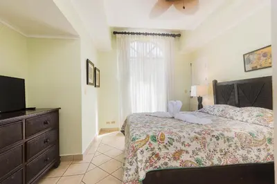 a bedroom with a bed with a dresser and a television at Sunrise 33- 3 Bedroom Poolside Condo in Tamarindo