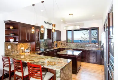 a kitchen with wooden cabinets and a large marble counter top at 360 Splendor 207A-Ocean View 2 Br Condo-Breakfast Included! in Playa Flamingo