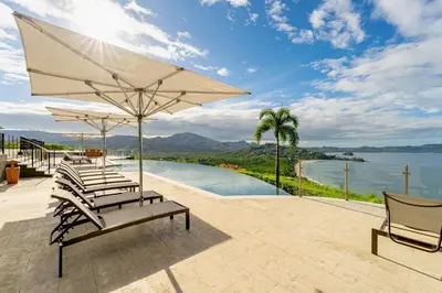 a group of chairs and an umbrella next to a pool at 360 Splendor 206-Ocean View Condo-Breakfast Included! in Playa Flamingo