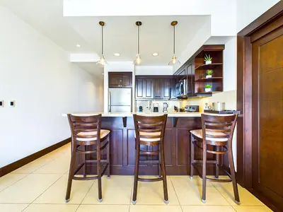 a kitchen with wooden cabinets and a bar with stools at 360 Splendor 301-Ocean View Condo-Breakfast Included! in Playa Flamingo