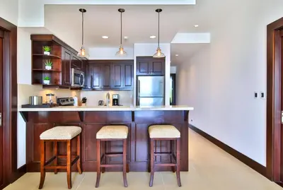 a kitchen with wooden cabinets and a counter with stools at 360 Splendor 303-Ocean View Condo-Breakfast Included! in Playa Flamingo