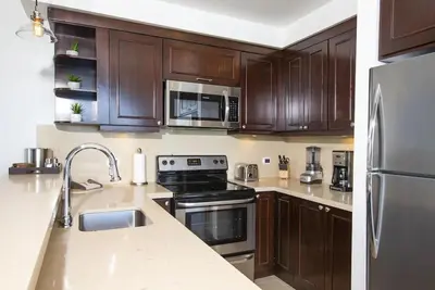 a kitchen with wooden cabinets and stainless steel appliances at 360 Splendor 101F Ocean View 2Br Breakfast in Playa Flamingo