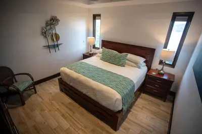 a bedroom with a bed and two lamps and a chair at 360 Splendor 207B-Ocean View Condo-Breakfast in Playa Flamingo