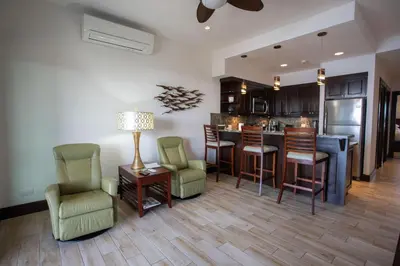 a living room with a kitchen with a bar and chairs at 360 Splendor 207B-Ocean View Condo-Breakfast in Playa Flamingo