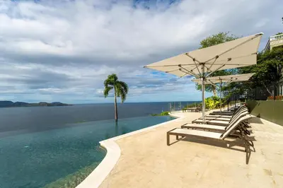 a group of chairs and an umbrella and the water at 360 Splendor 207B-Ocean View Condo-Breakfast in Playa Flamingo