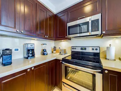 a kitchen with wooden cabinets and a stove and microwave at 360 Splendor 405 Ocean View Condo- With Breakfast in Playa Flamingo