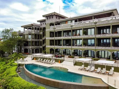 a hotel with a swimming pool in front of a building at 360 Splendor 308B Ocean View Condo- With Breakfast in Playa Flamingo