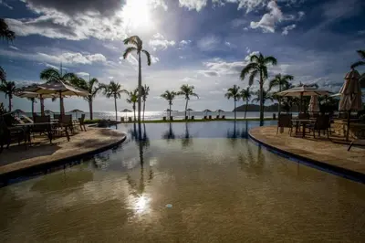 a pool at a resort with palm trees and the ocean at Palms 14 Luxury Beachfront Villa in Playa Flamingo