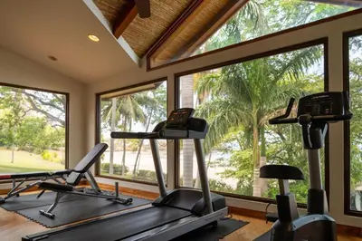 a gym with three elliptical machines and windows at Palms 5 Luxury Beachfront Villa in Playa Flamingo