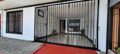 a metal gate on a building with two potted plants at Panda House in Quepos