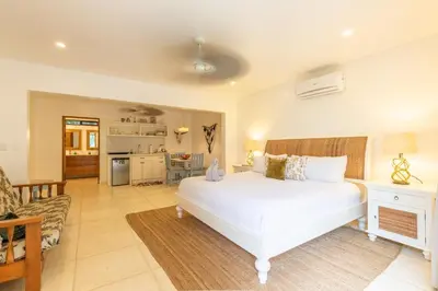 a bedroom with a white bed and a living room at Casa Vitality Bed and Breakfast - Playa Guiones, Nosara - 4 Minute Walk to the Beach in Nosara