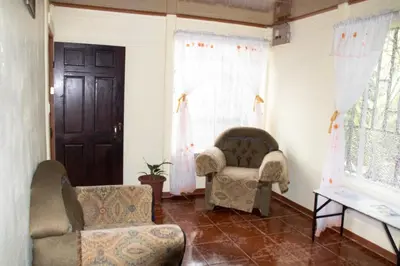 a living room with two chairs and a door at The Corner House - Hospedaje con Encanto en Tortuguero in Tortuguero