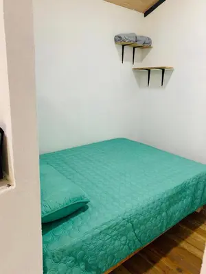 a bed in a room with a green comforter at Cabañas del Bosque in Nandayure