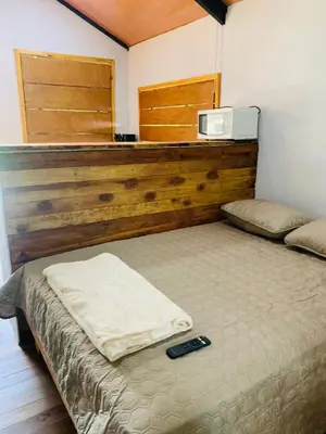 a bedroom with a bed with a remote control on it at Cabañas del Bosque in Nandayure