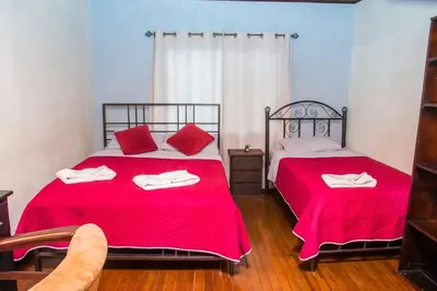 two beds in a room with red sheets at Alojamiento entero 1 km Juan Santamaría Airport in Alajuela City