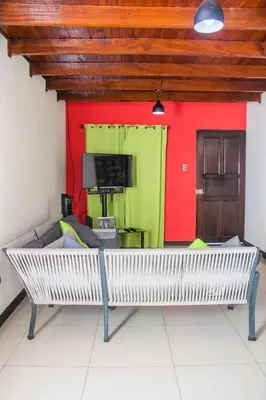 a bench in a room with a red and green wall at Alojamiento entero 1 km Juan Santamaría Airport in Alajuela City