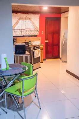 a kitchen with a table and chairs and a kitchen with red at Alojamiento entero 1 km Juan Santamaría Airport in Alajuela City