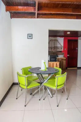 a dining room with a table and green chairs at Alojamiento entero 1 km Juan Santamaría Airport in Alajuela City