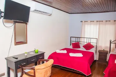 a bedroom with a bed with a red blanket and a desk at Alojamiento entero 1 km Juan Santamaría Airport in Alajuela City