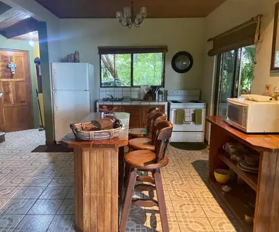 a kitchen with wooden stools and a counter with a refrigerator at Casa de veraneo Quinta Las Trillizas in Esparza
