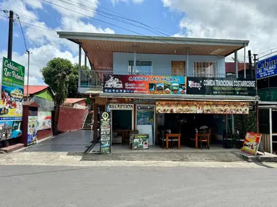 a store on the side of a street with a building at Cabinas Las Palmas del Sol in Fortuna