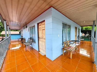 a porch with chairs and tables on a house at Cabinas Las Palmas del Sol in Fortuna