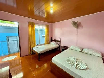 a bedroom with two beds and a window at Cabinas Las Palmas del Sol in Fortuna