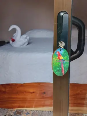 a door handle with a bird on it next to a bed at Habitación a 26 kilómetros de Jaco, Tulin Azul in Jacó