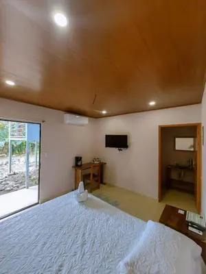 a bedroom with a large white bed and a television at Habitación a 26 kilómetros de Jaco, Tulin Azul in Jacó