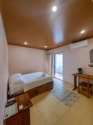 a bedroom with a bed and a table and a window at Habitación a 26 kilómetros de Jaco, Tulin Azul in Jacó