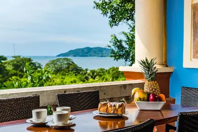 a table with a bowl of fruit and a plate of food at El Diria 302- 2 Bedroom Ocean View Condo in Tamarindo