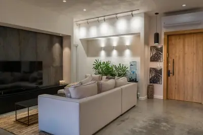 a living room with a white couch and a television at Casa Olala Santa Teresa in Santa Teresa Beach