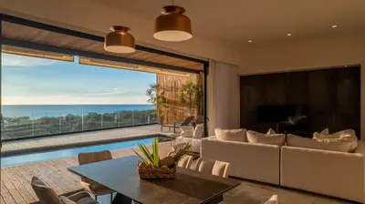 a living room with a table and a view of the ocean at Casa Olala Santa Teresa in Santa Teresa Beach