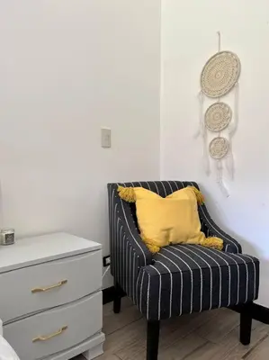 a black and white chair with a yellow pillow next to a dresser at CR MARIPOSA RENTALS Lakeview PENTHOUSE with office space, pool, gym, tennis in Santa Ana