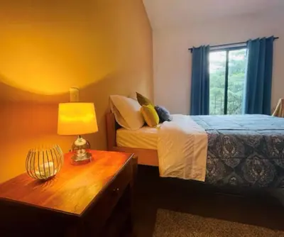 a bedroom with a bed and a table with a lamp at Cozy and Peaceful Beach Apartment in Playa Grande