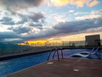 a swimming pool on top of a building with a sunset at iFreses, Study Full equipped whith Pool, air- conditioning, spectacular view of the city, parking with additional payment in Curridabat