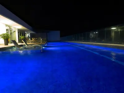 a large swimming pool at night with blue illumination at iFreses, Study Full equipped whith Pool, air- conditioning, spectacular view of the city, parking with additional payment in Curridabat