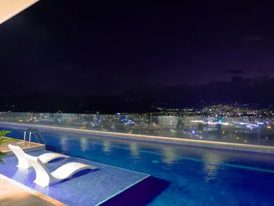 a pool with two white chairs on top of a building at iFreses, Study Full equipped whith Pool, air- conditioning, spectacular view of the city, parking with additional payment in Curridabat